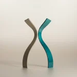 Single ribbon-like sculpture splitting into two, one branch fading to gray on a soft neutral background.